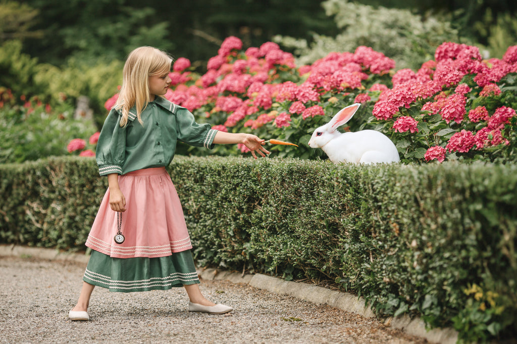 girl standing in beautifull summer dress near a rabbit
